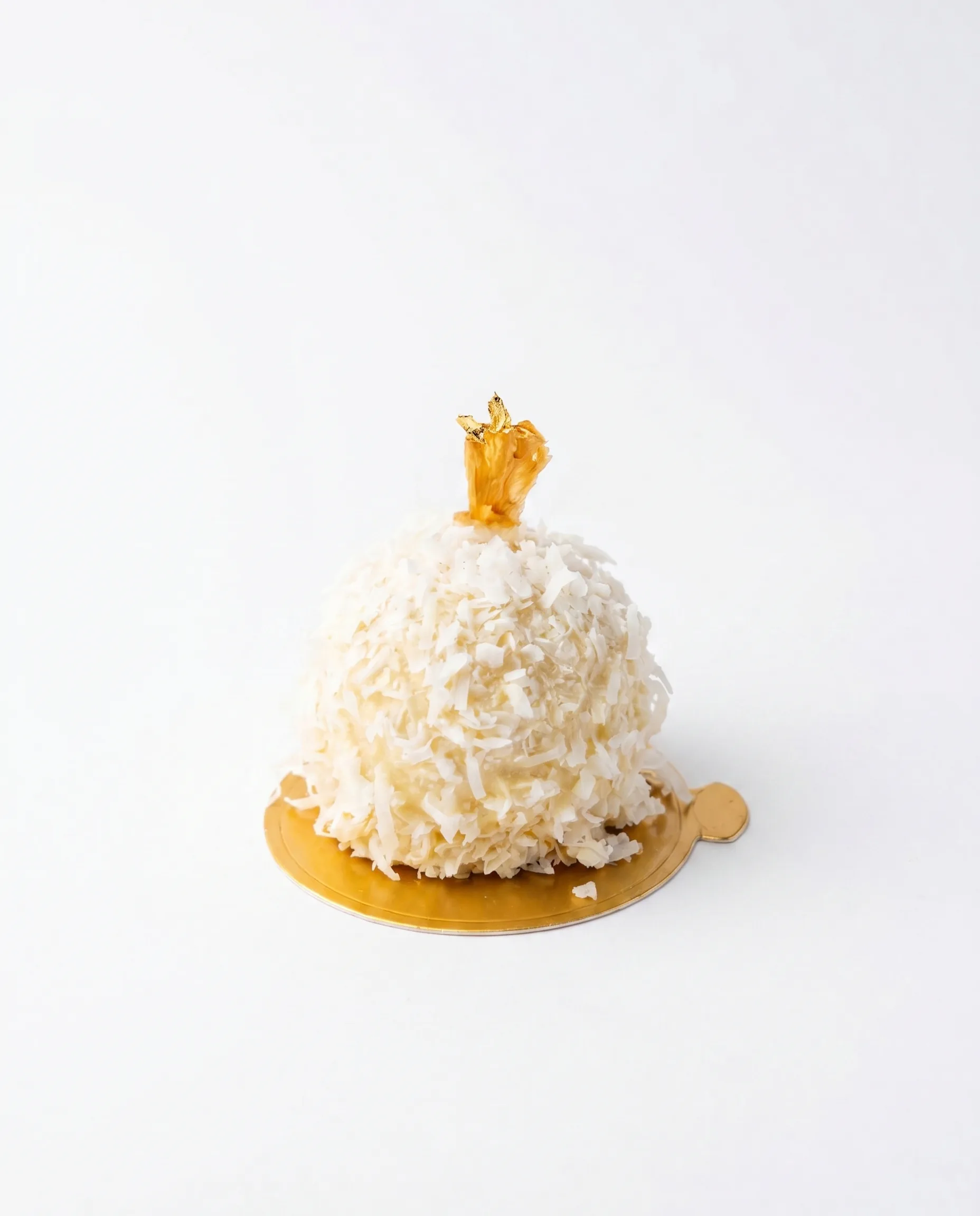 Coco Ananas — Silky coconut cream and bright pineapple filling enveloped in a pristine white chocolate shell, crowned with toasted shredded coconut.